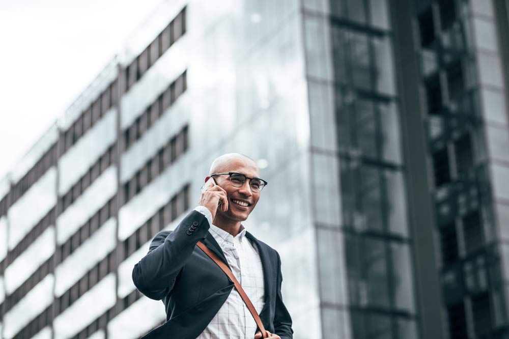 Man pratar i telefon och har höghus bakom